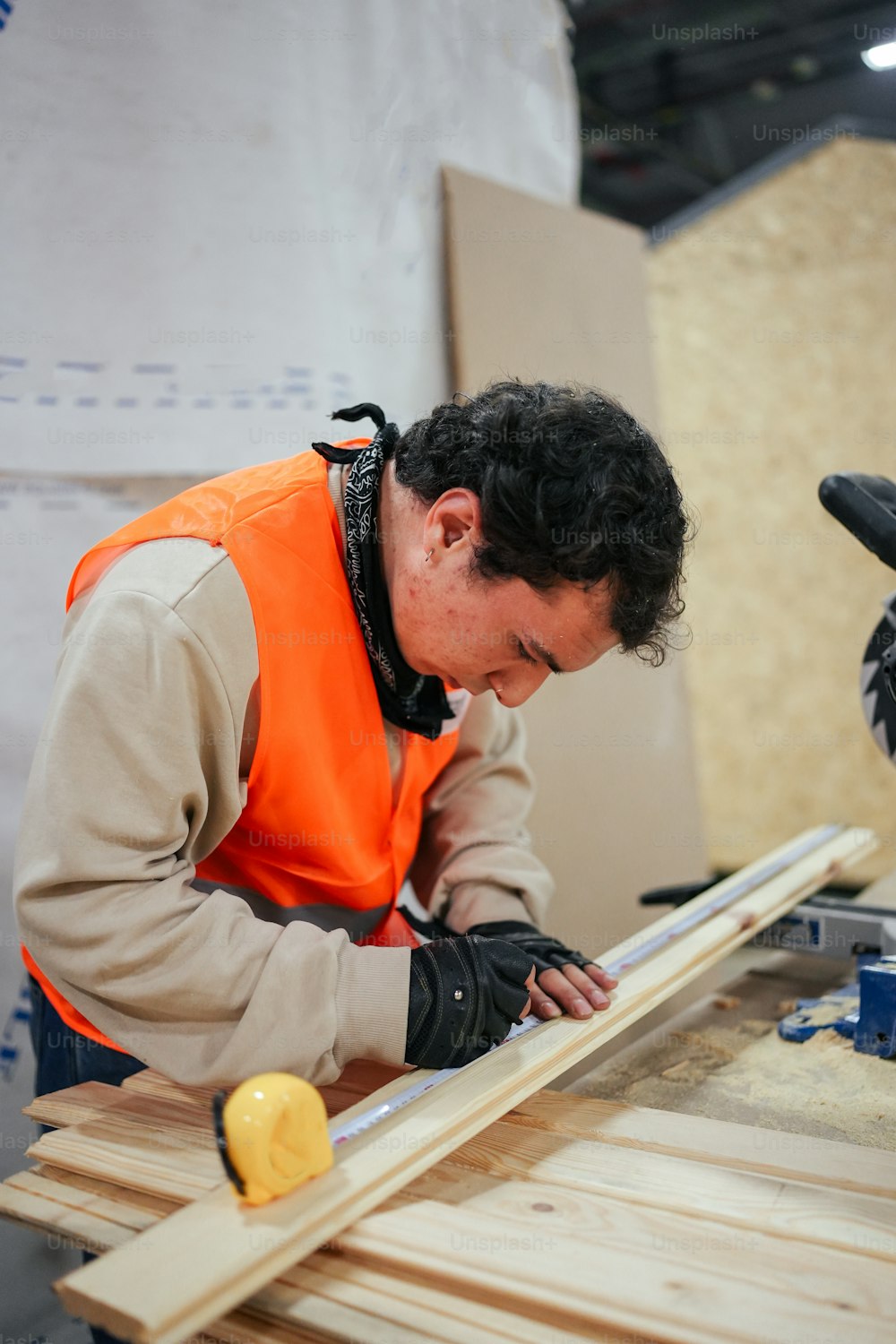 주황색 조끼를 입은 남자가 나무 조각을 작업하고 있다