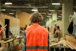 Ein Mann in orangefarbener Warnweste steht in einer Fabrik