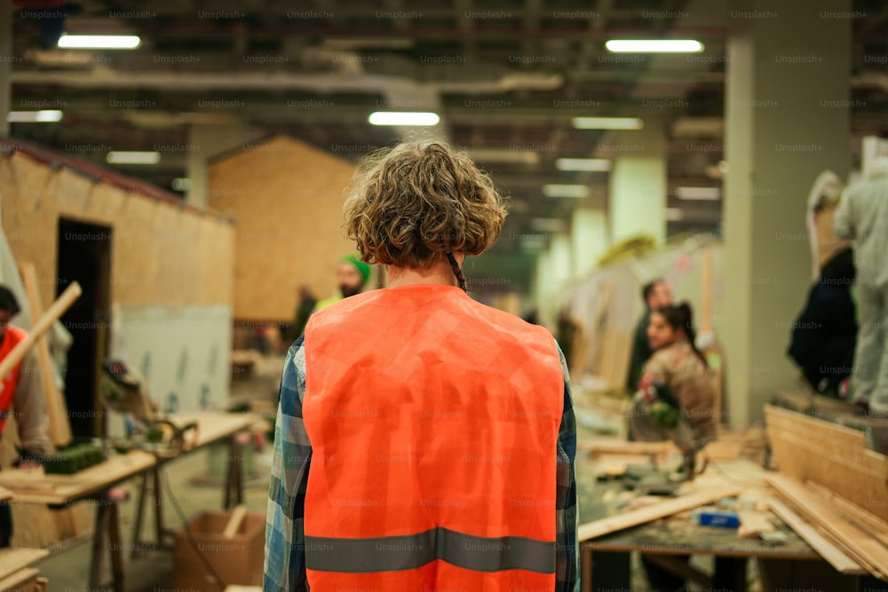 a man in an orange safety vest standing in a factory