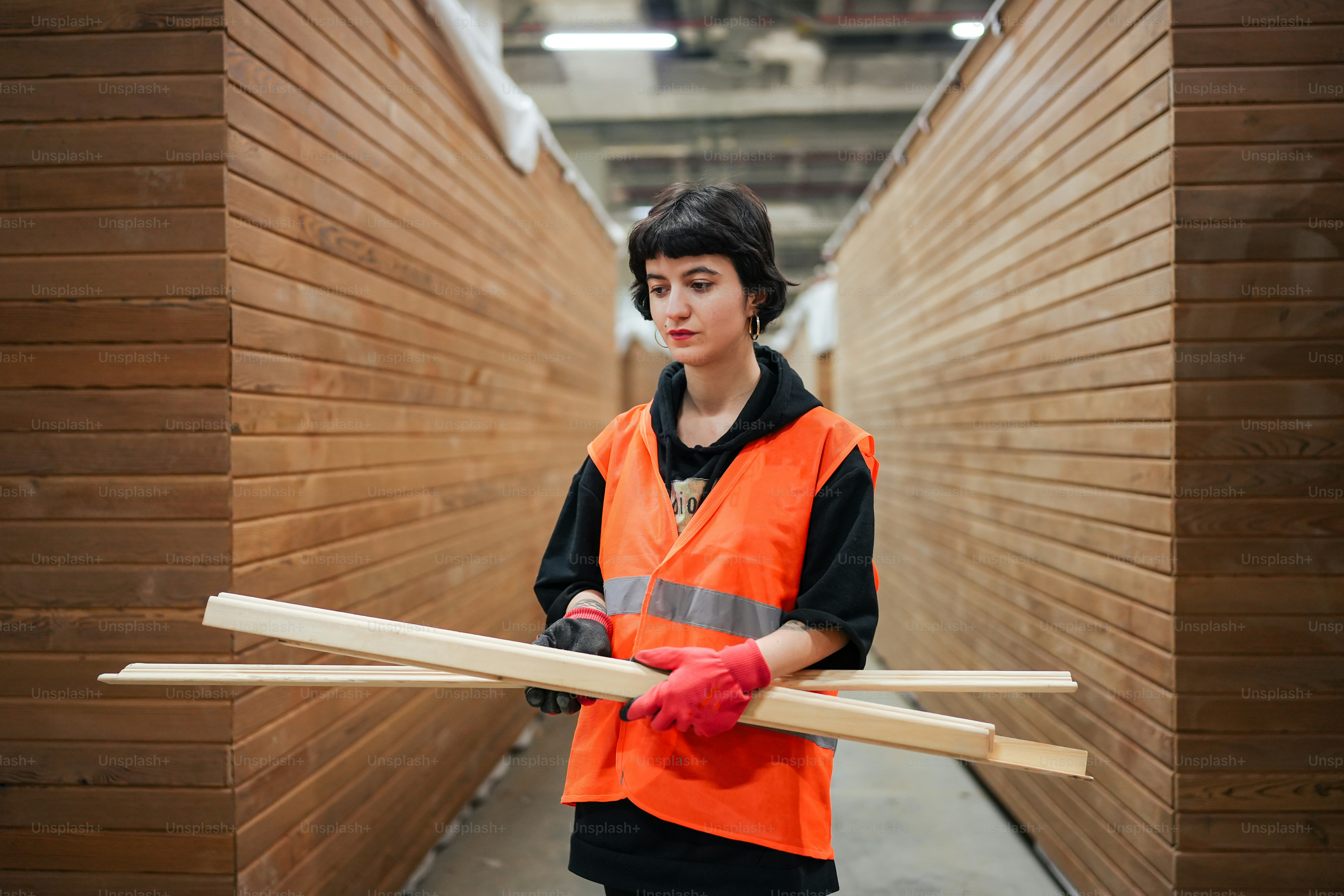 a woman in an orange vest holding a pair of wooden planks