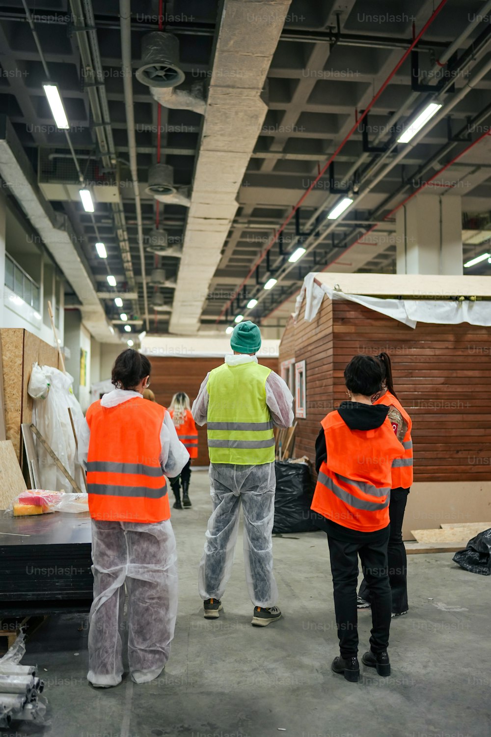 a group of people in orange vests standing in a warehouse