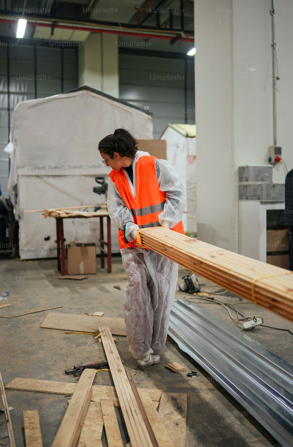 Eine Frau in einer orangefarbenen Weste bei der Arbeit an einem Stück Holz