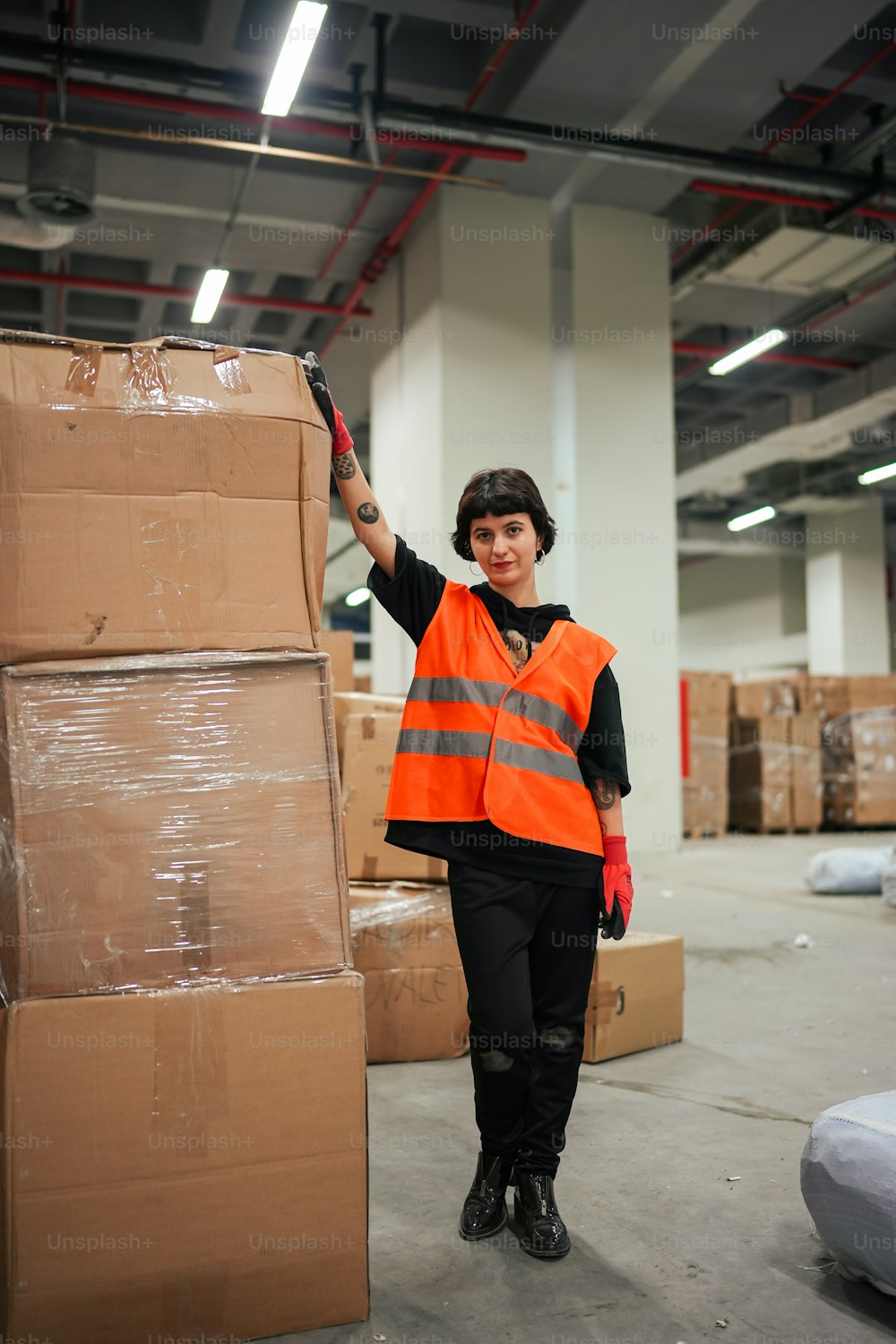 a woman in an orange vest is holding a box
