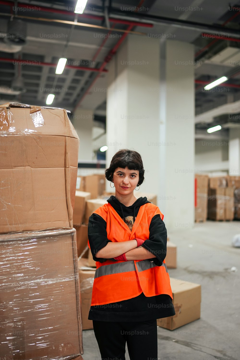 a woman in an orange vest standing in a warehouse
