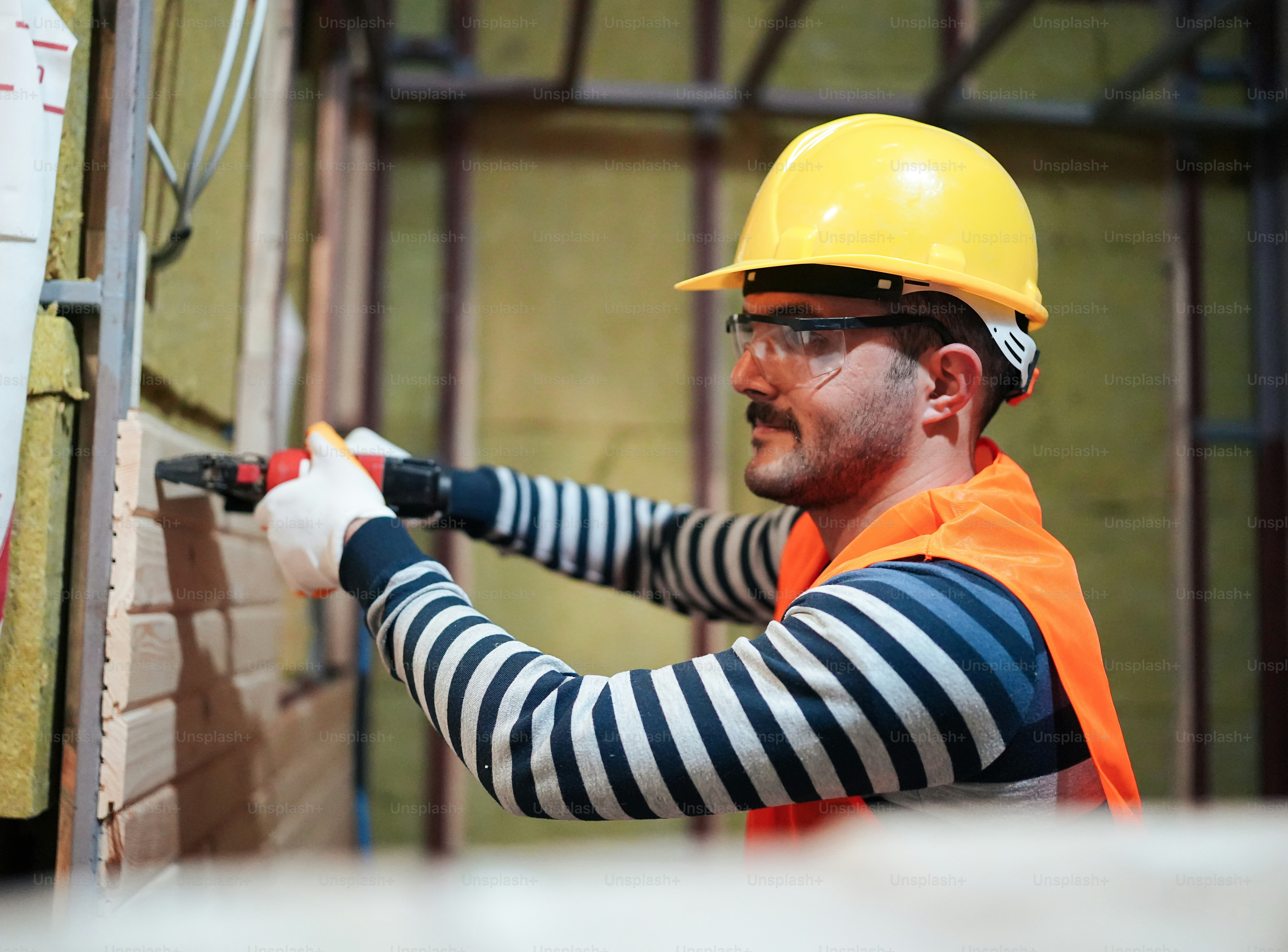 a man in a hard hat and safety vest working on a brick wall