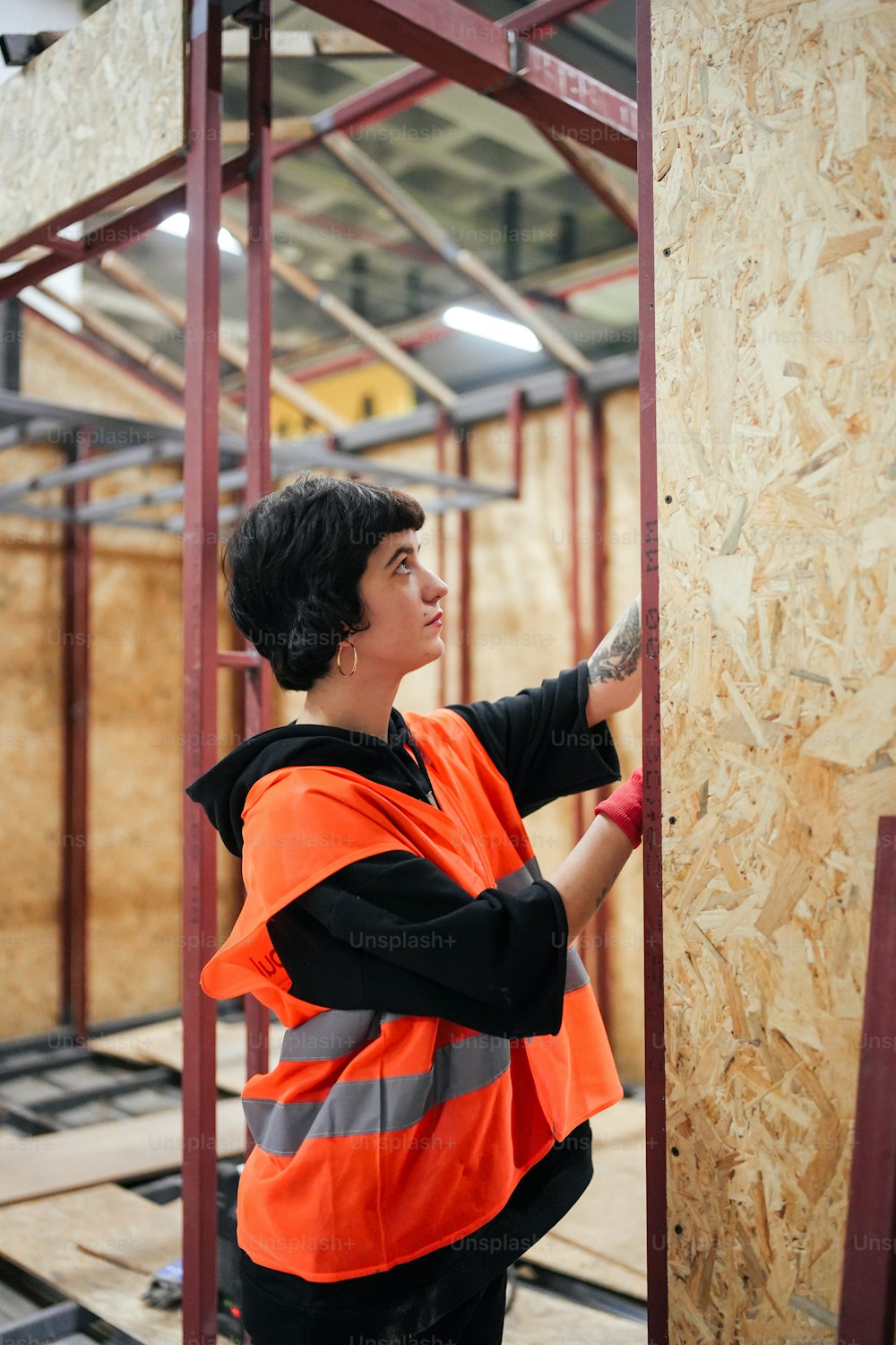 a woman in an orange vest is working on a wall