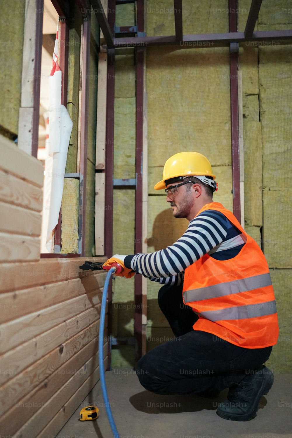 a man in a hard hat and safety vest working on a wall