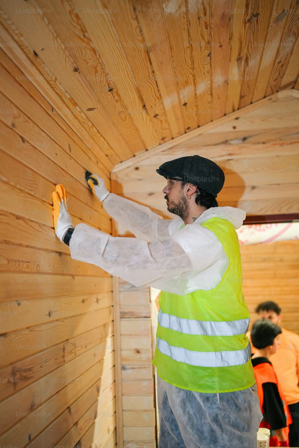 a man in a yellow vest painting a wooden wall