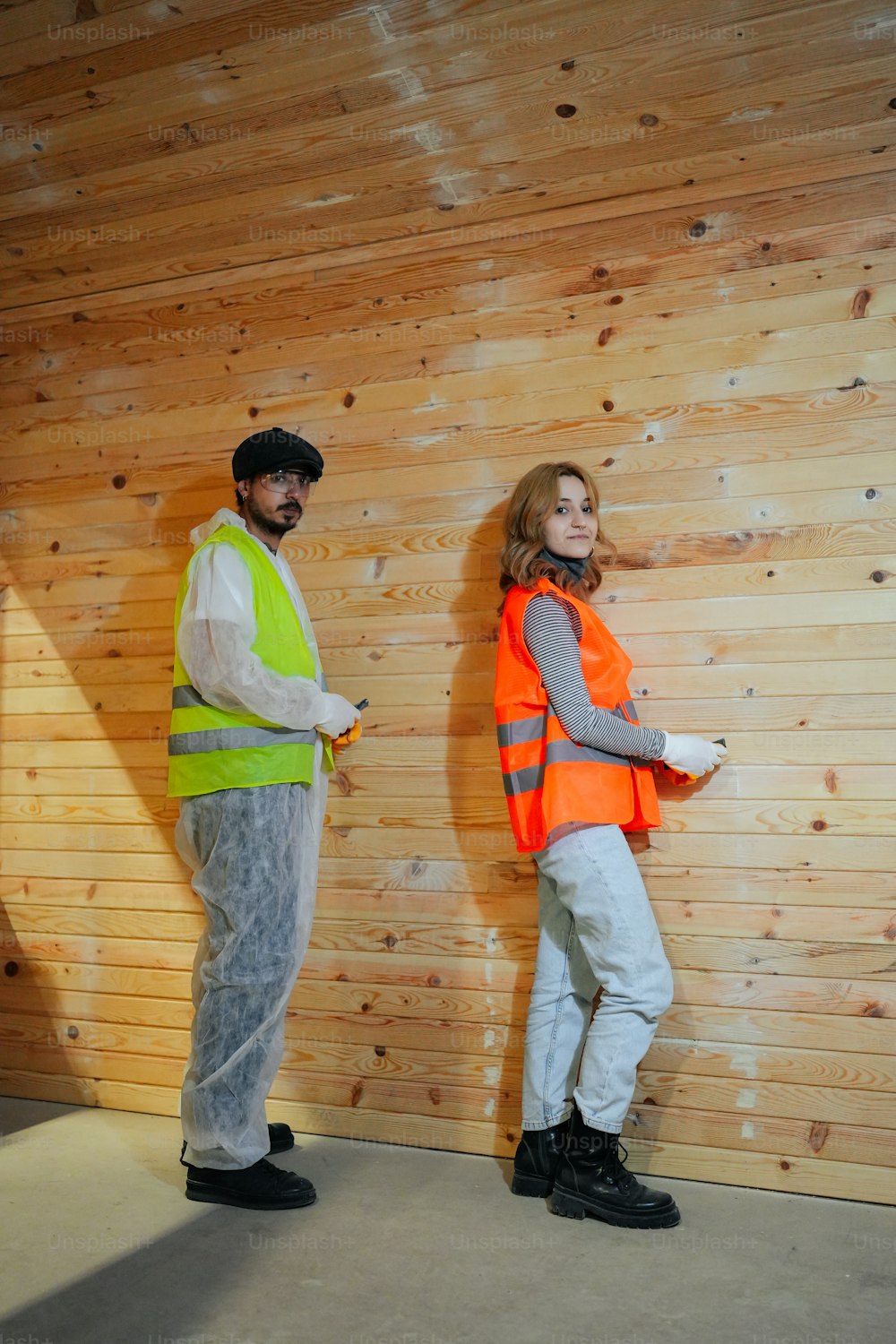 a man and a woman standing in front of a wooden wall