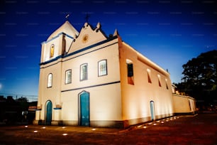 Una iglesia iluminada por la noche con un reloj en el frente