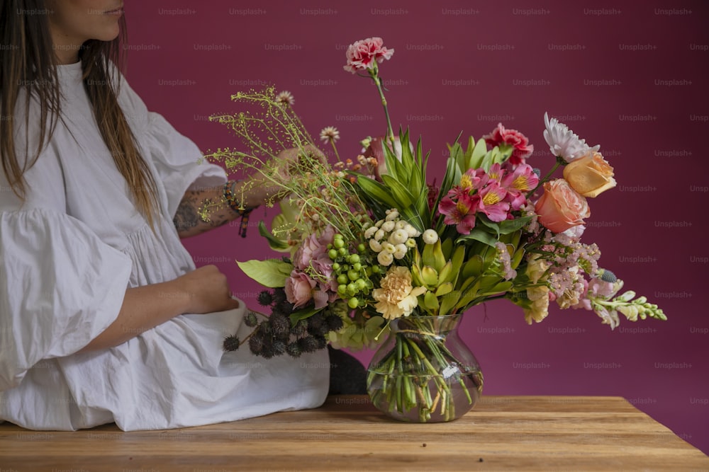 uma mulher sentada em uma mesa com um vaso de flores