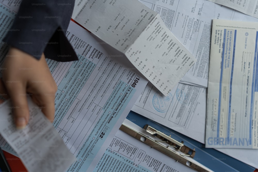 a pile of papers with a person's hand on top of them