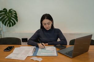 Una mujer sentada en una mesa con una computadora portátil y papeles