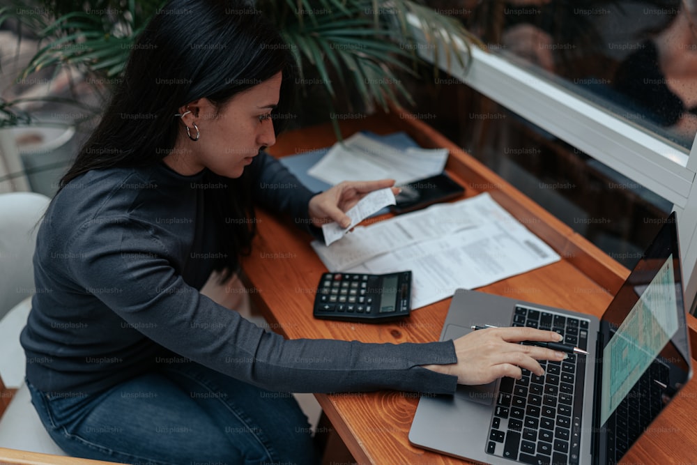 Una mujer sentada en un escritorio con una computadora portátil y una calculadora