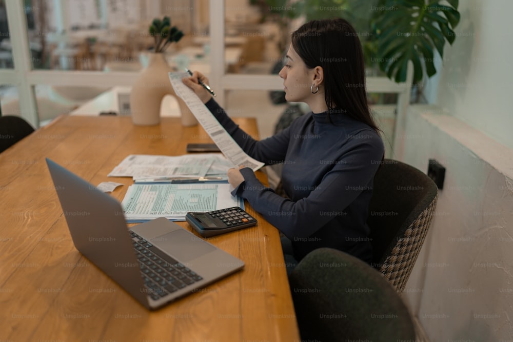 Una mujer sentada en una mesa con una computadora portátil y una calculadora