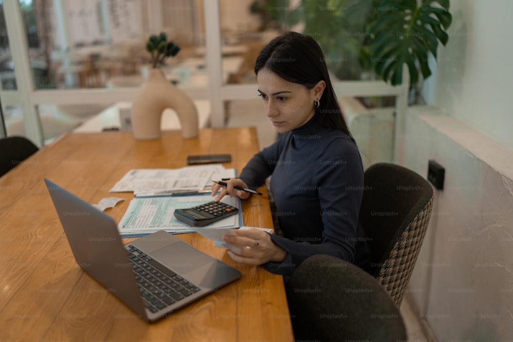Una mujer sentada en una mesa con una calculadora y una computadora portátil