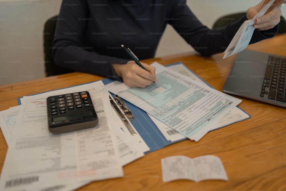 Una donna seduta a un tavolo con una calcolatrice e un computer portatile