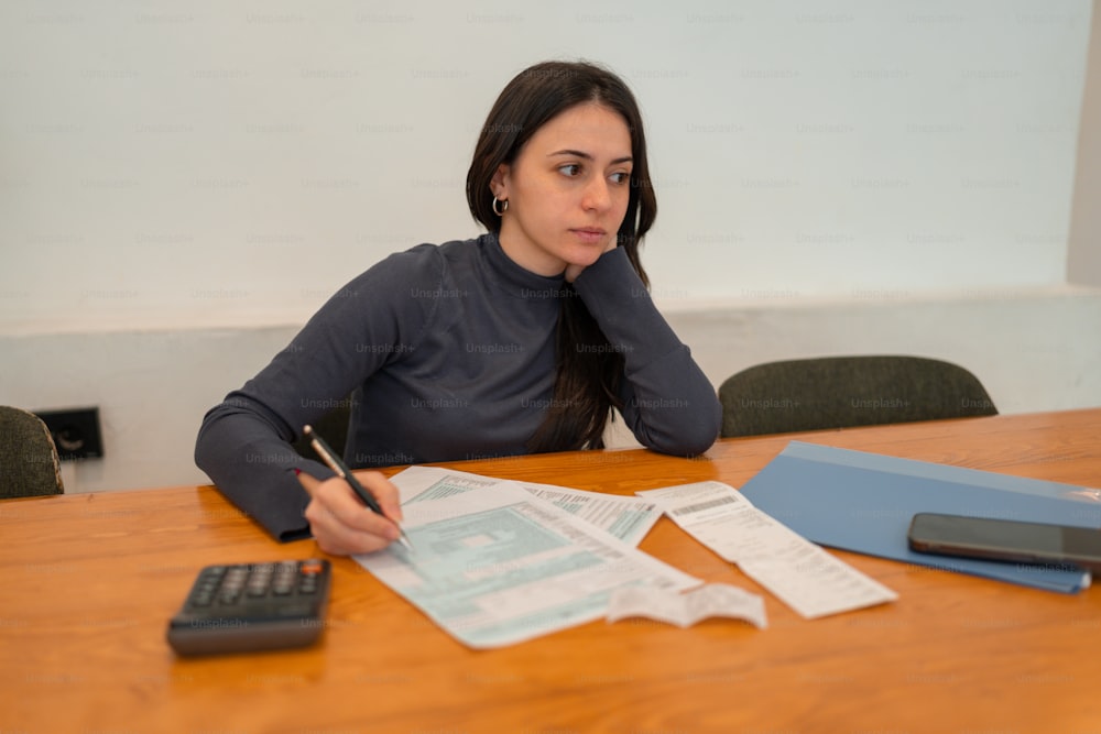 a woman sitting at a table with a calculator