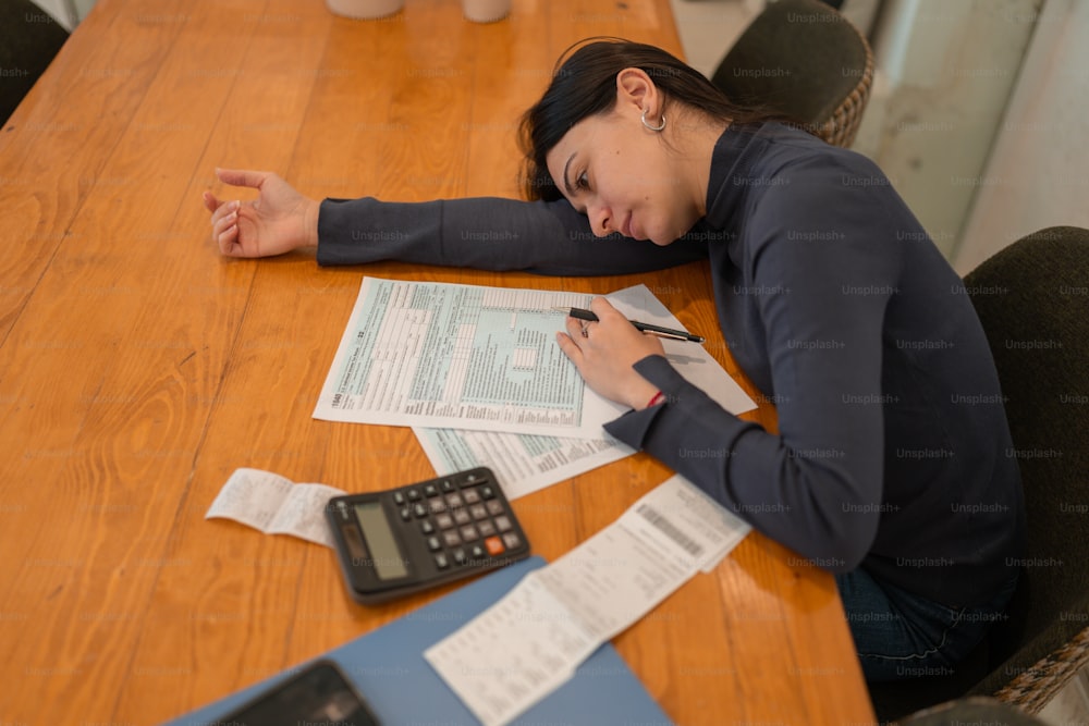 a woman sitting at a table with a calculator