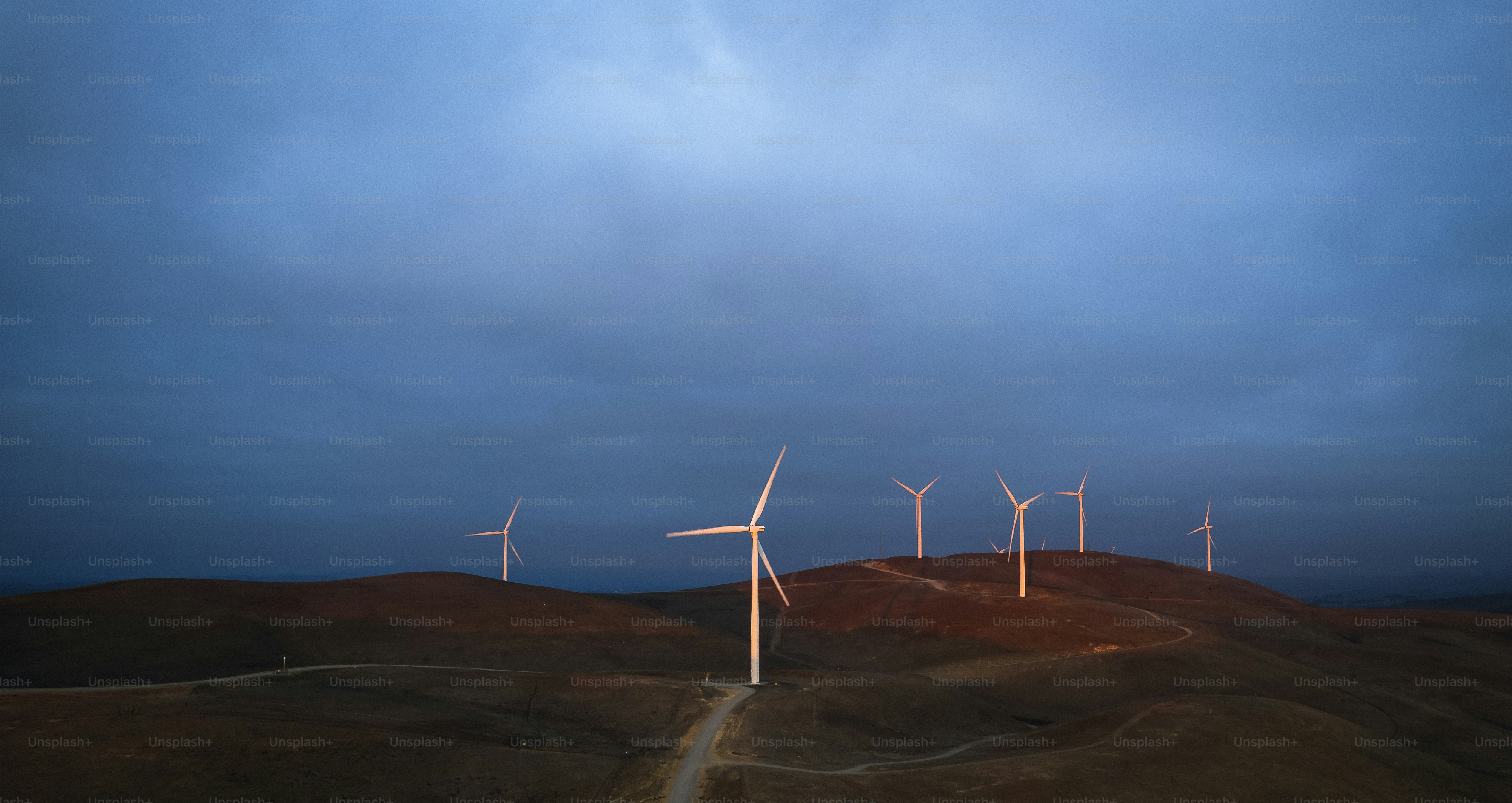 Un groupe de moulins à vent sur une colline sous un ciel nuageux