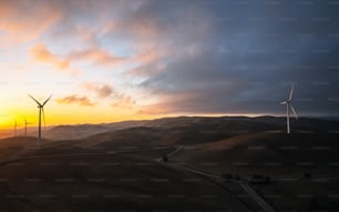 a group of windmills on a hill at sunset