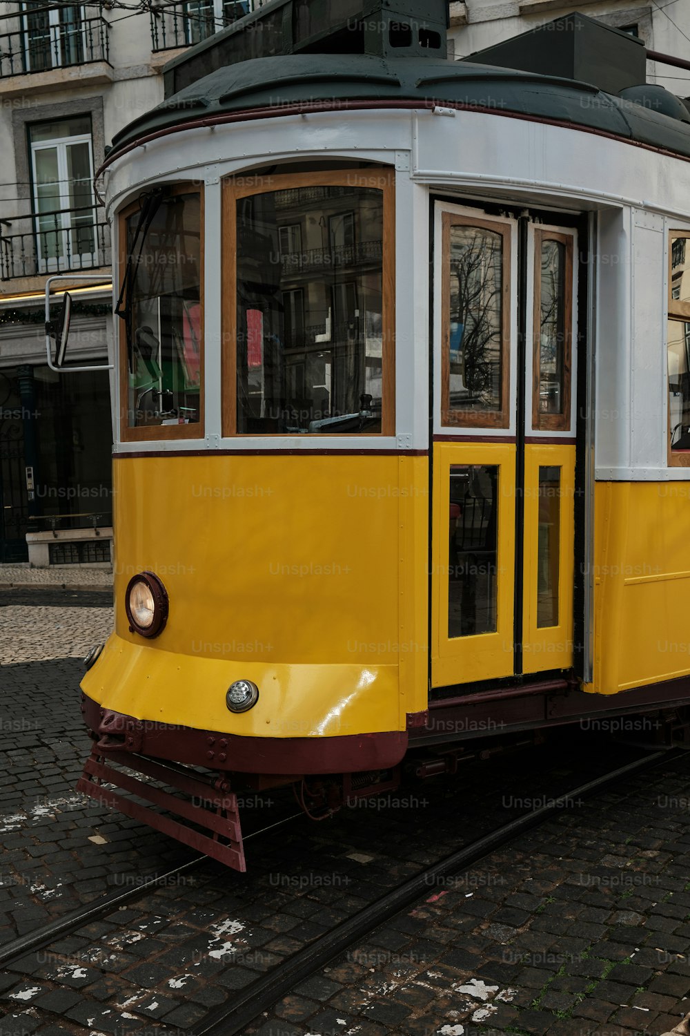 a yellow and white trolley car on a brick road