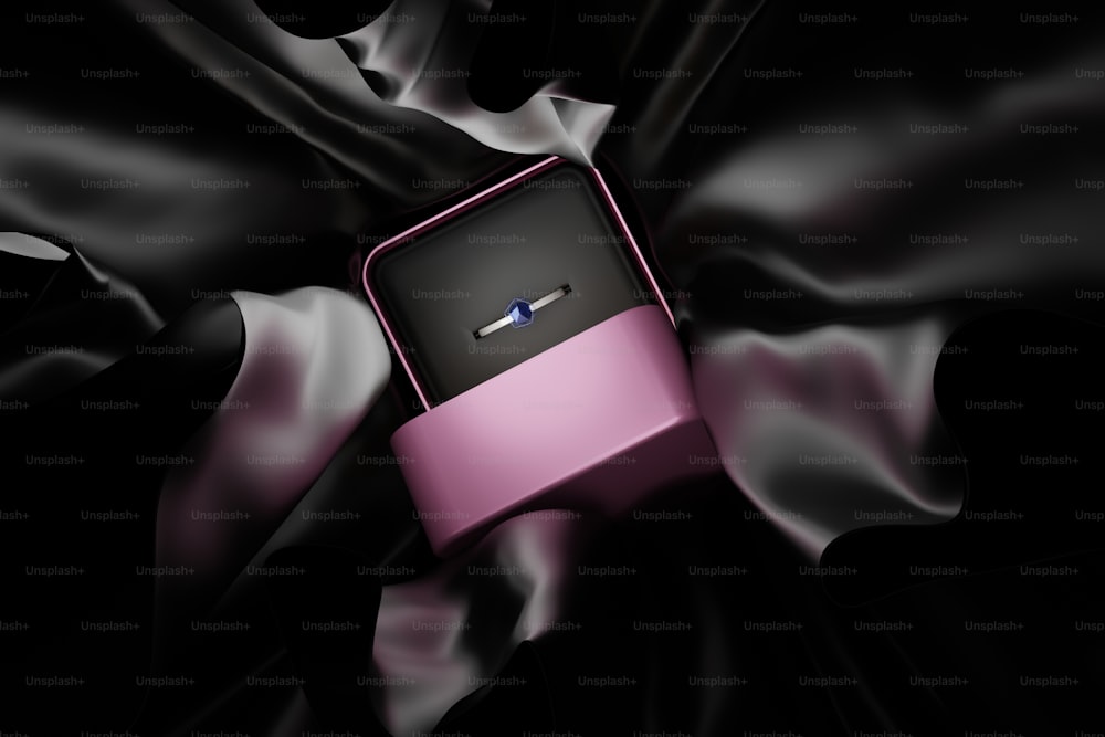 a pink and black box sitting on top of a black cloth