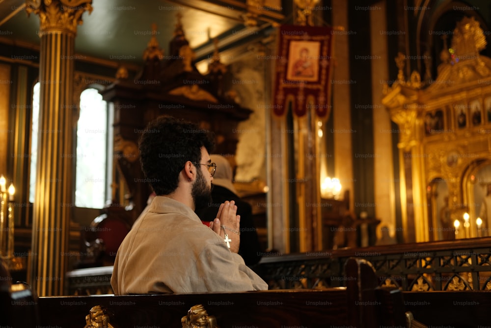 a man sitting in a church with his hands clasped