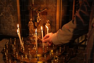 a person holding a lit candle in front of a statue