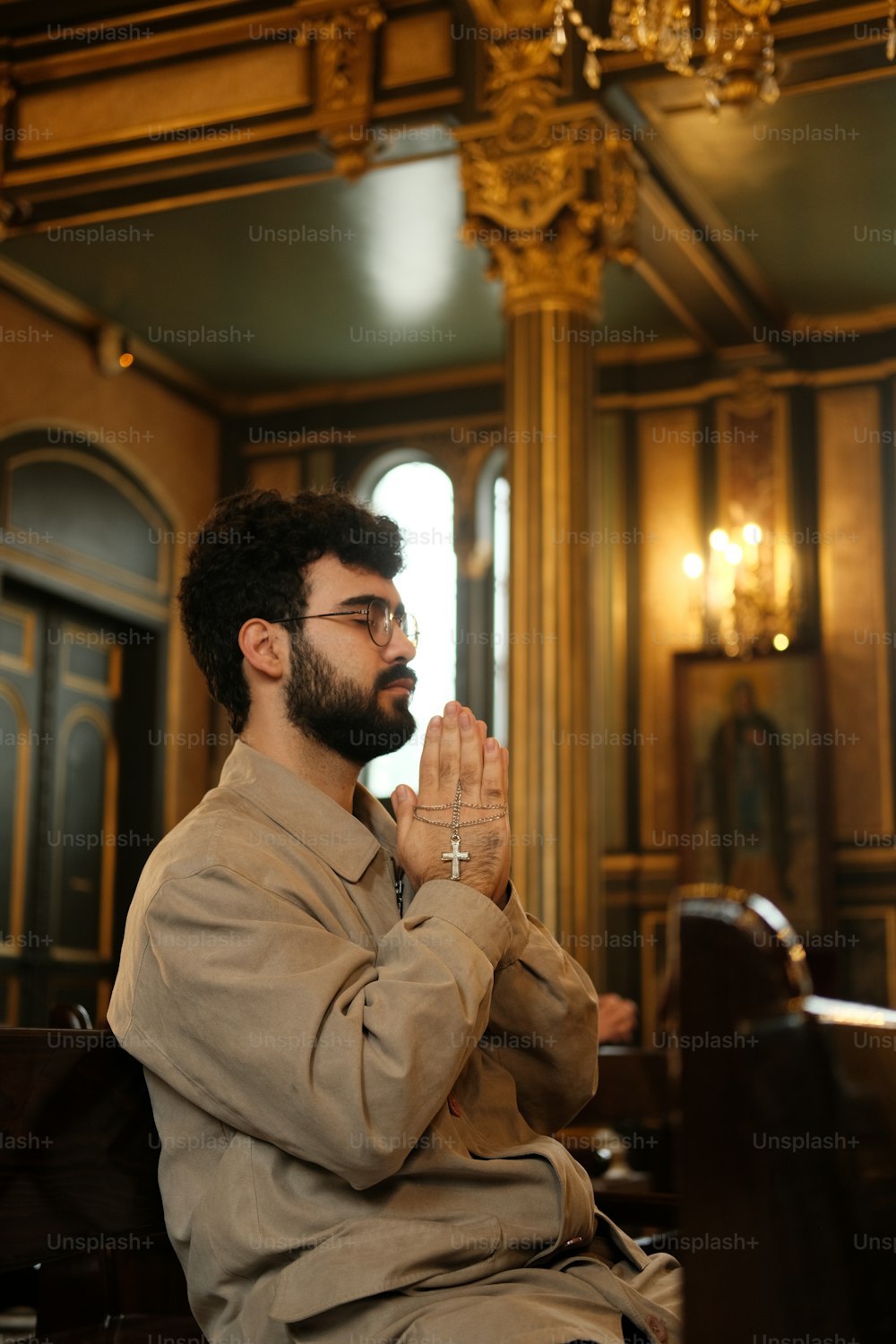 a man sitting in front of a chandelier praying