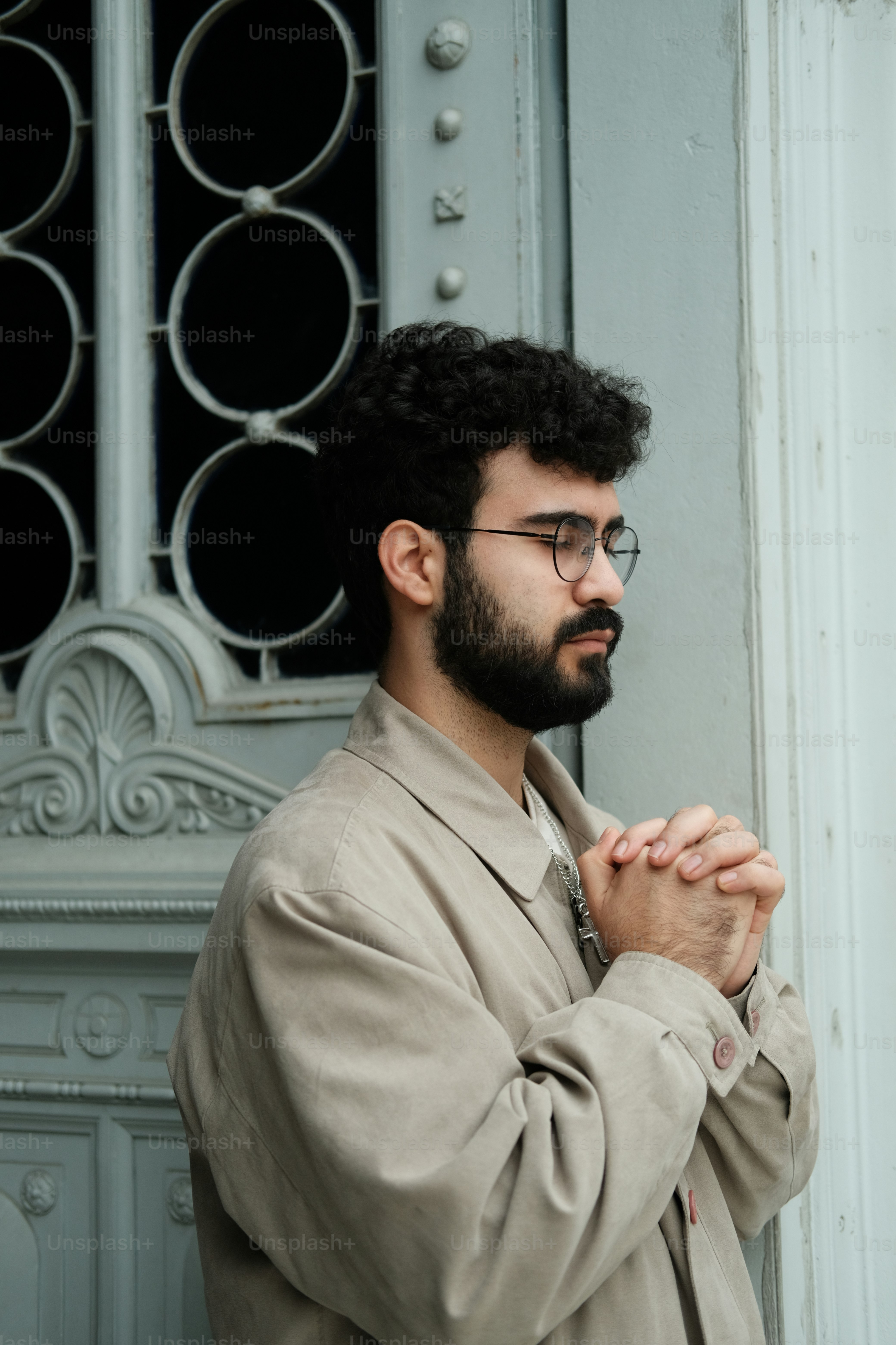 a man with a beard and glasses standing in front of a door