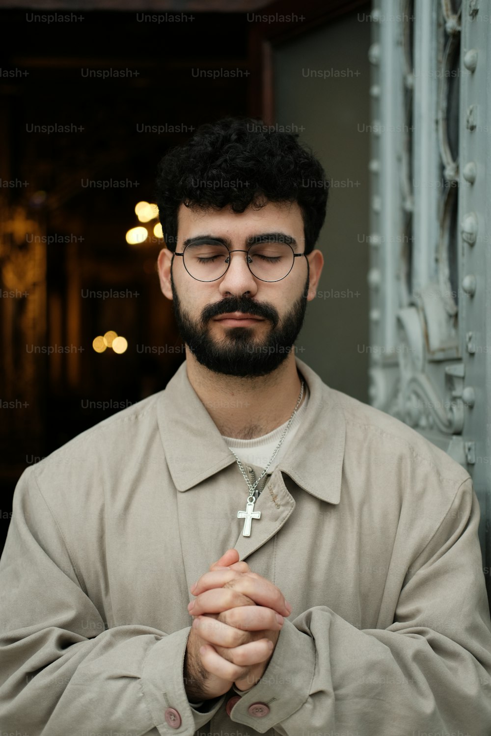 Un uomo con barba e occhiali che reggono una croce