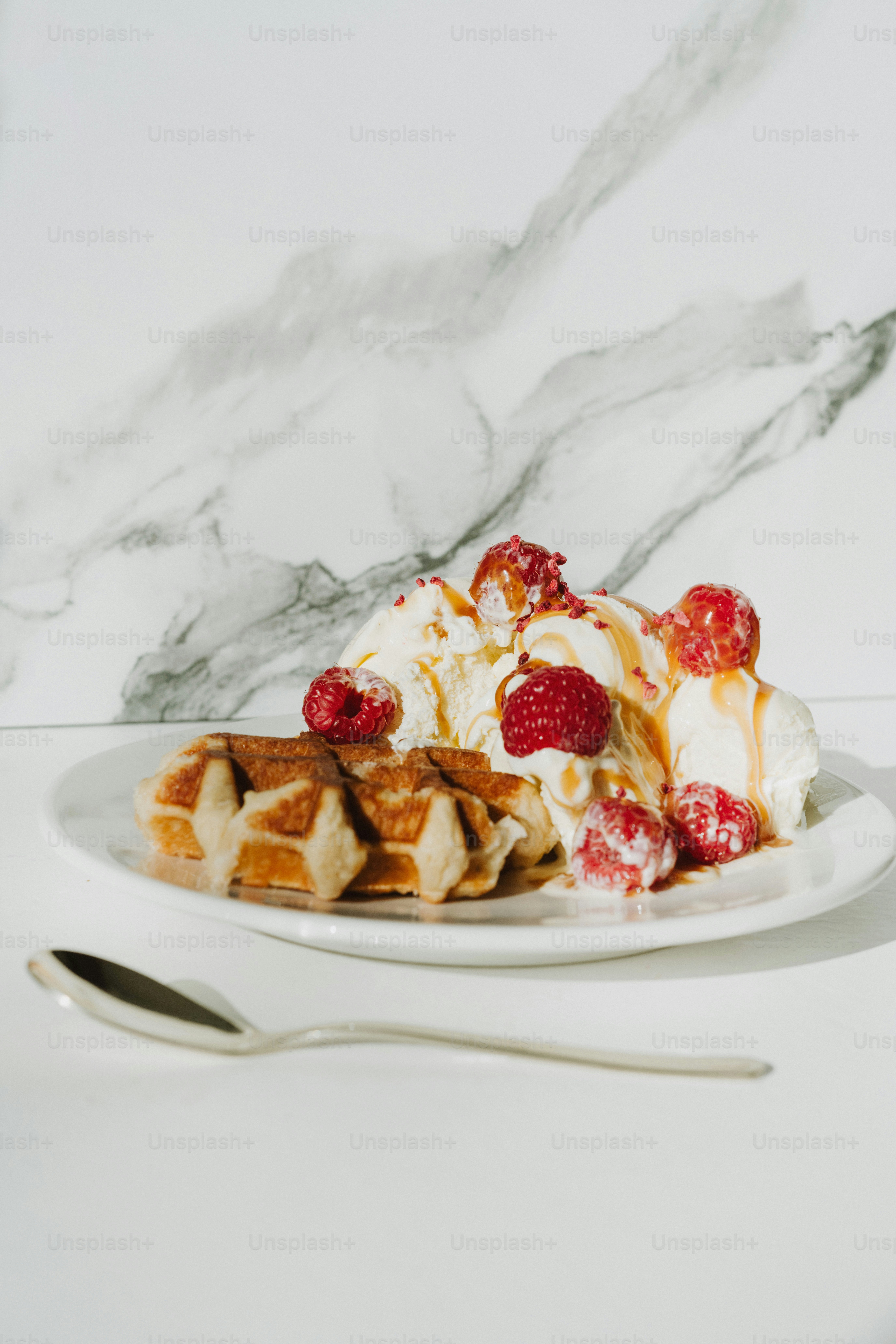 um prato branco coberto com waffles cobertos de chantilly e framboesas