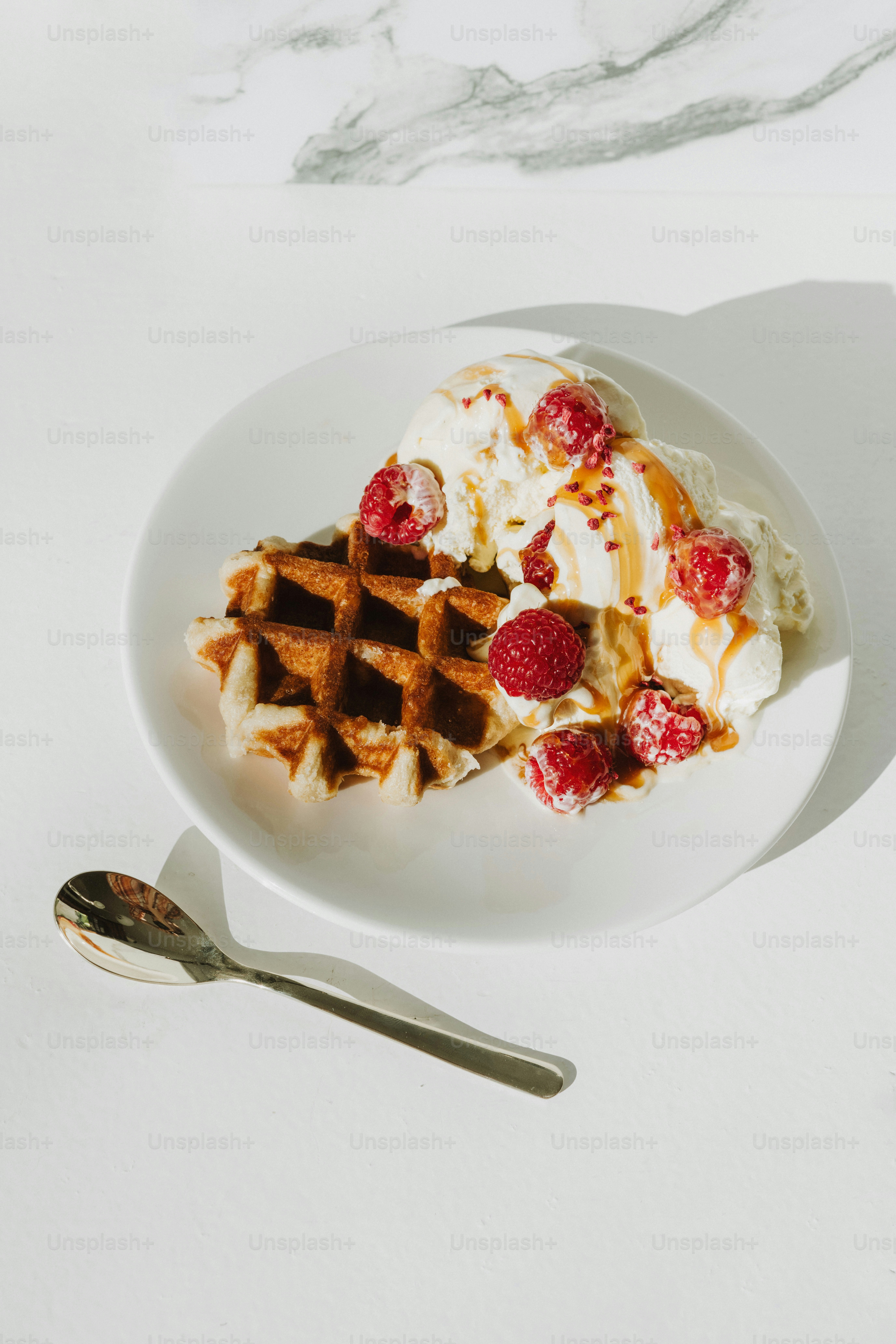 un plato blanco cubierto con gofres y helado