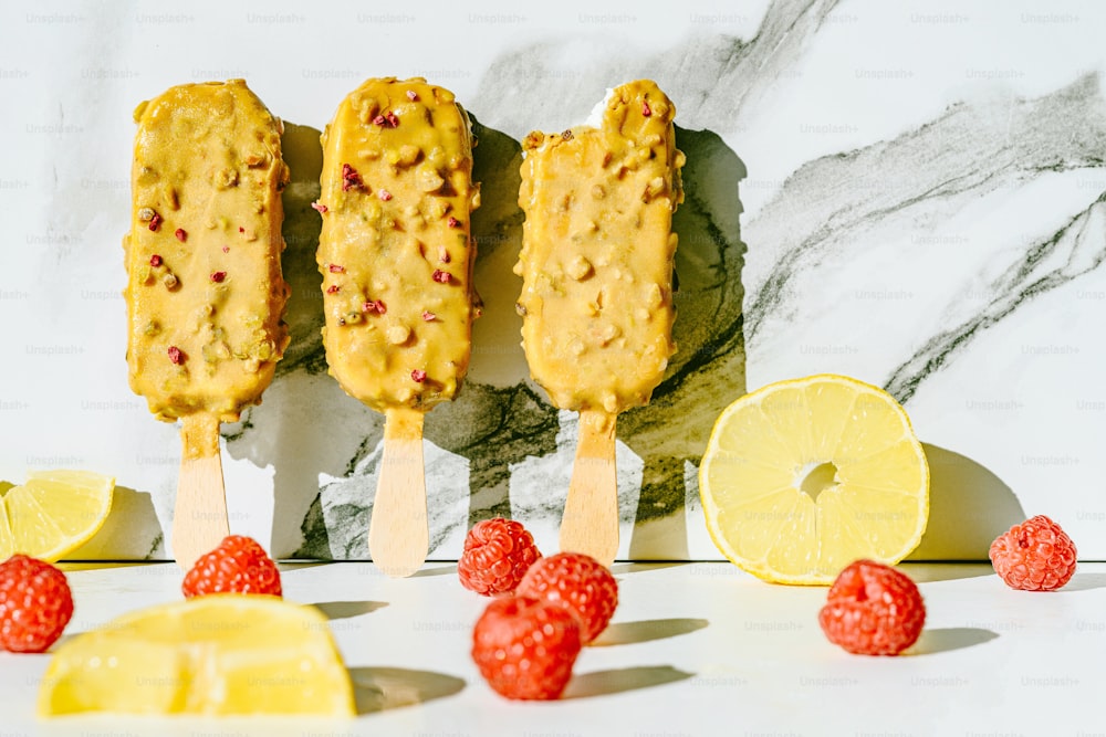 Tres paletas heladas en un palo con limones y frambuesas