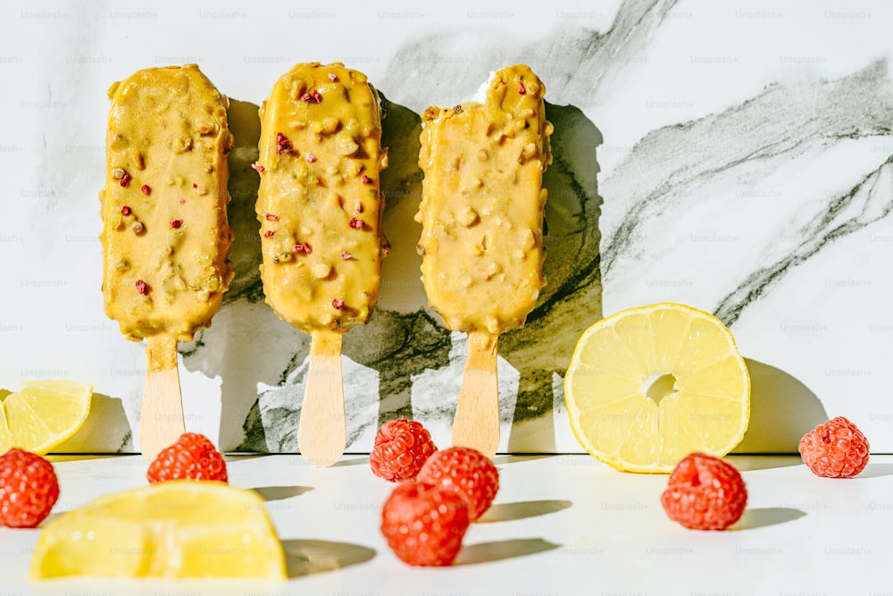 three popsicles on a stick with lemons and raspberries