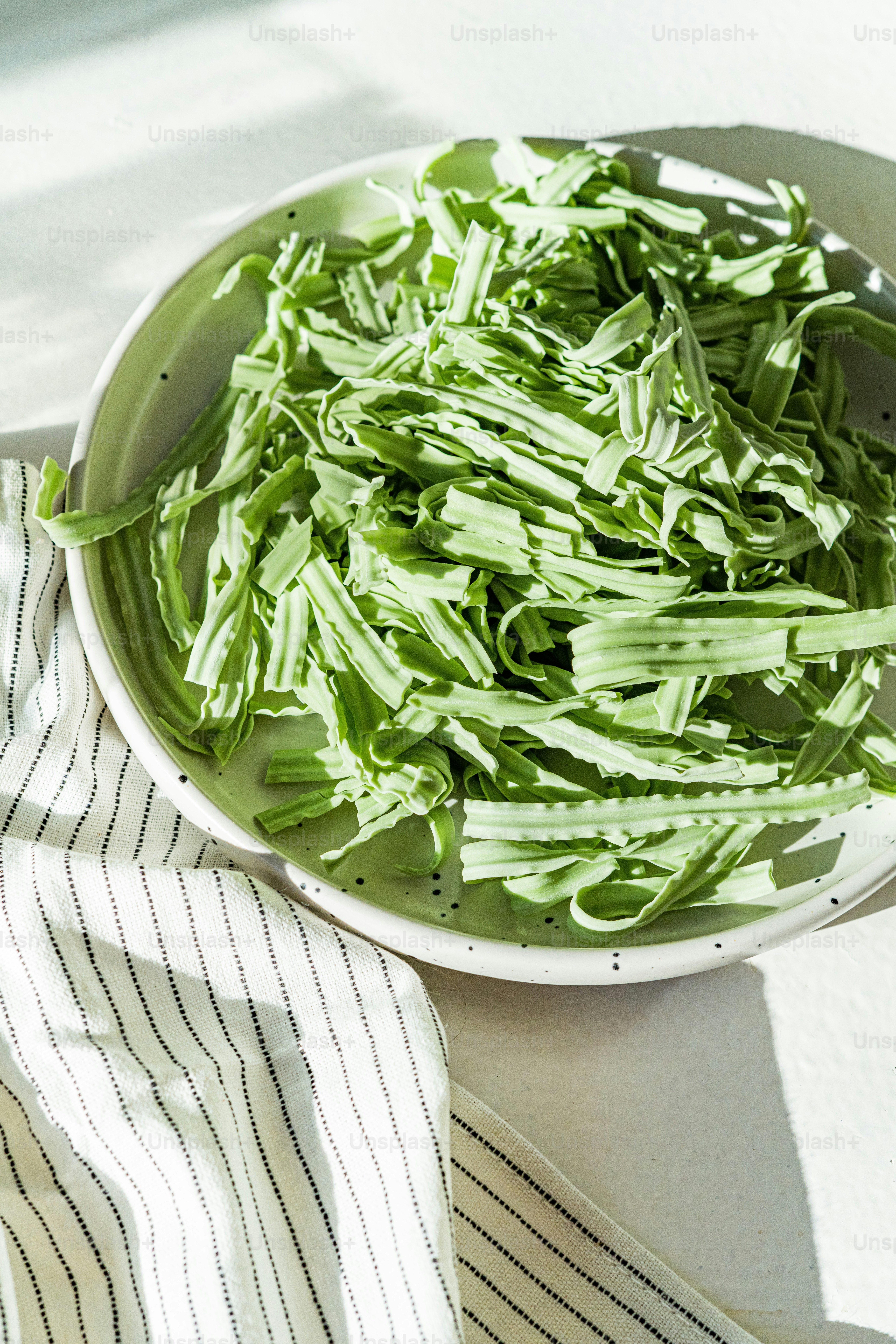 un tazón blanco lleno de verduras verdes encima de una mesa
