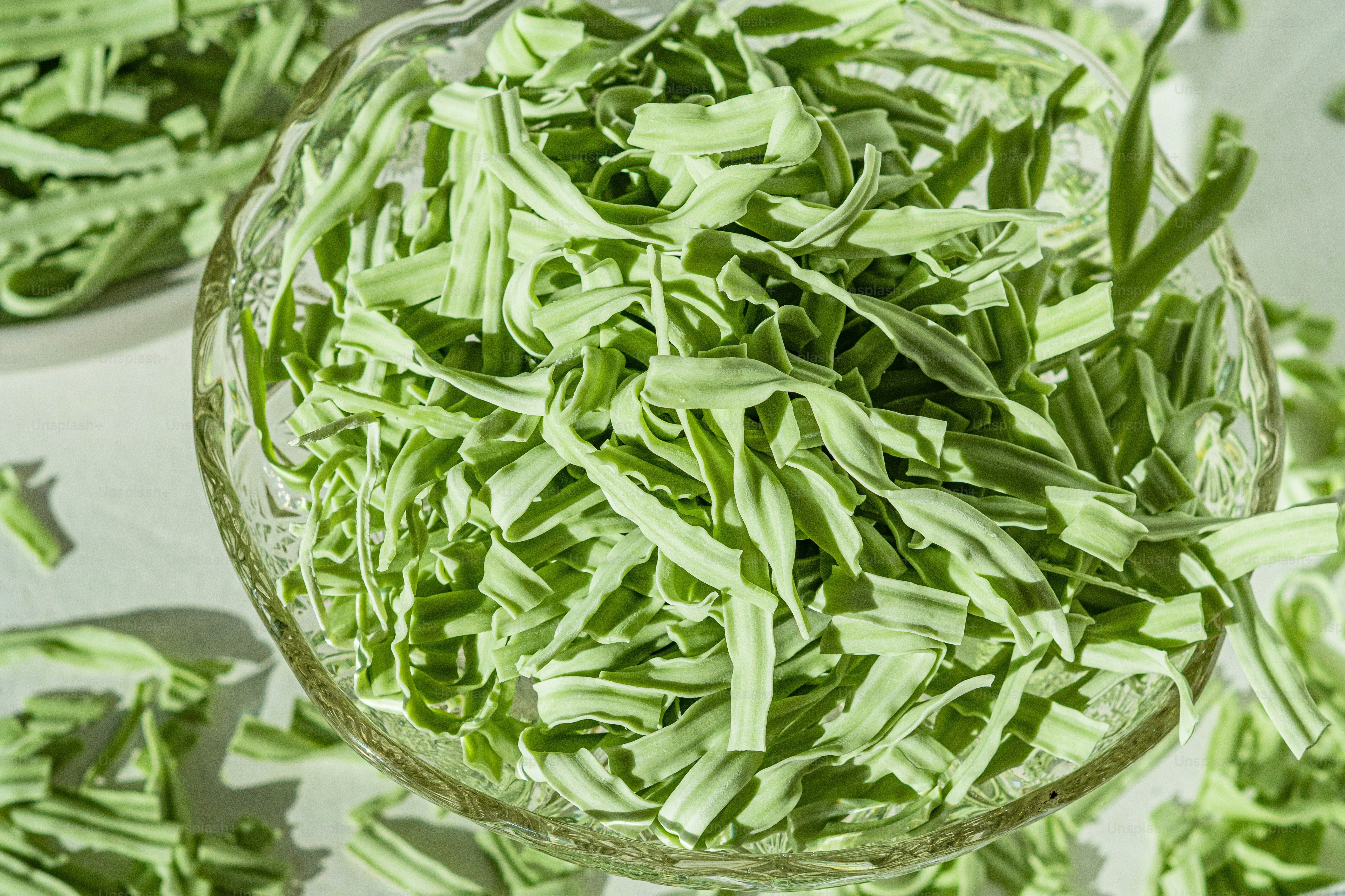 Un tazón de vidrio lleno de judías verdes encima de una mesa