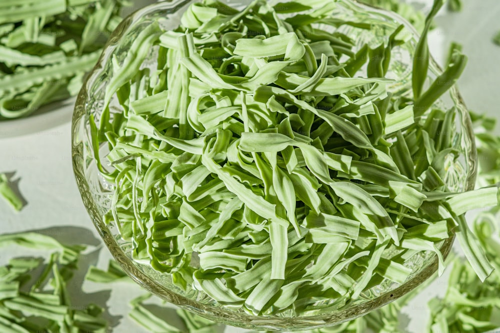 a glass bowl filled with green beans on top of a table