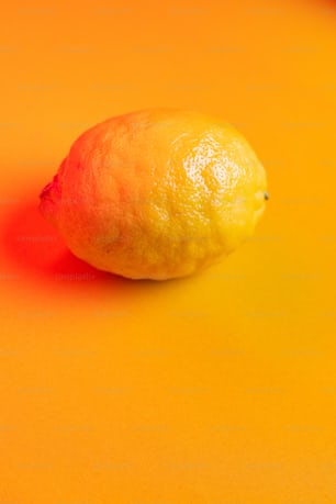 a single lemon sitting on a yellow surface