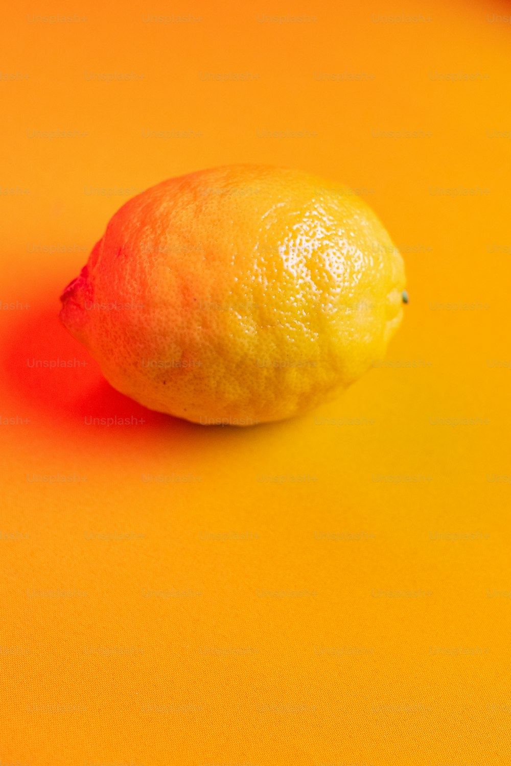 a single lemon sitting on a yellow surface