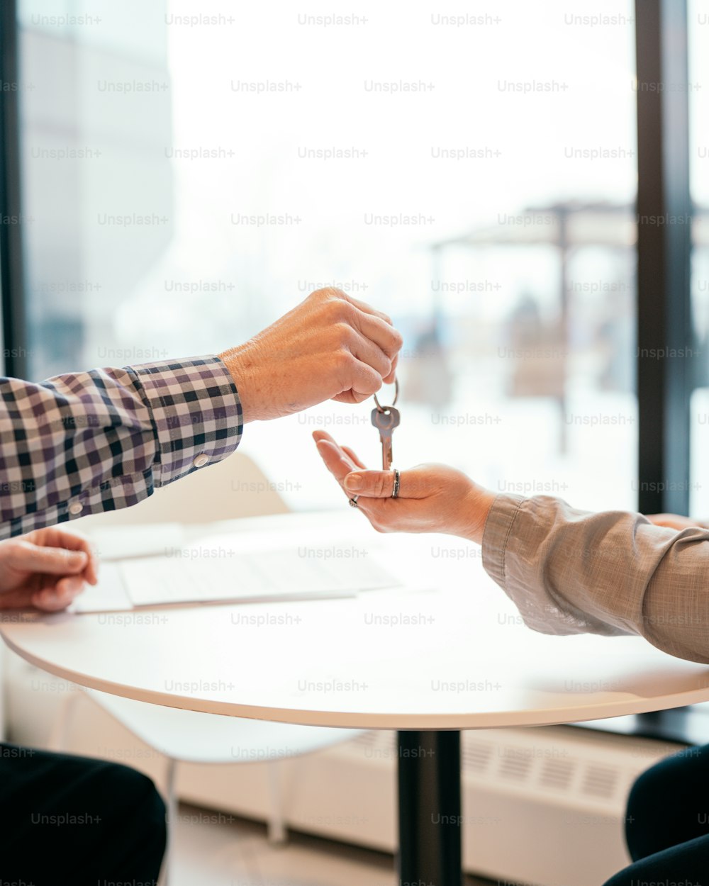 two people exchanging keys at a table