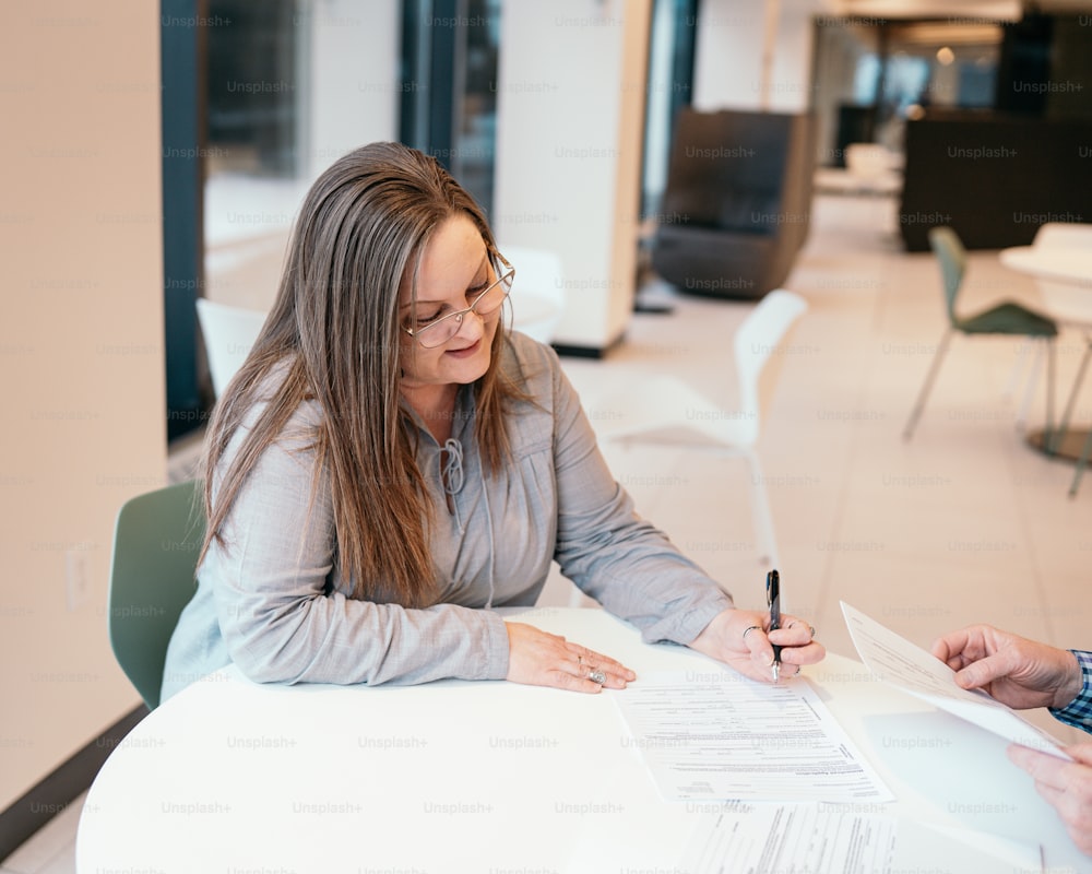 a woman sitting at a table signing a document