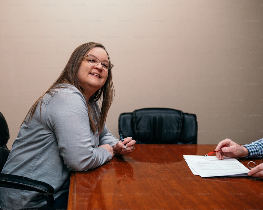 Une femme assise à une table signant un papier