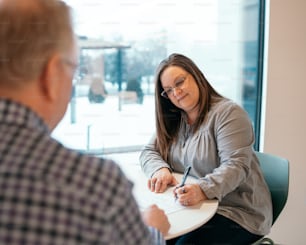 a woman sitting at a table writing on a piece of paper