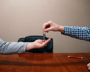 a person handing another person a key on a table