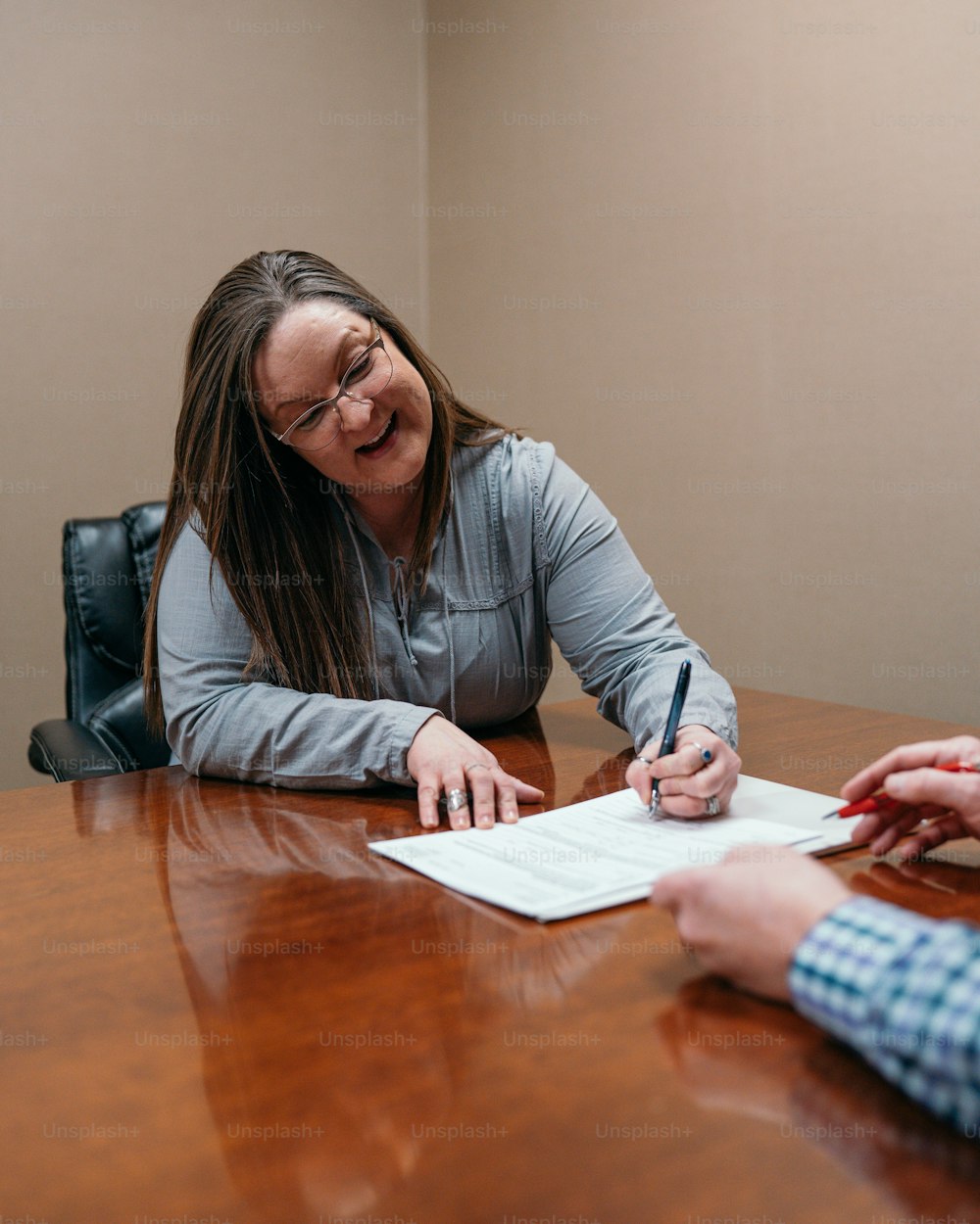 a woman sitting at a table signing a document
