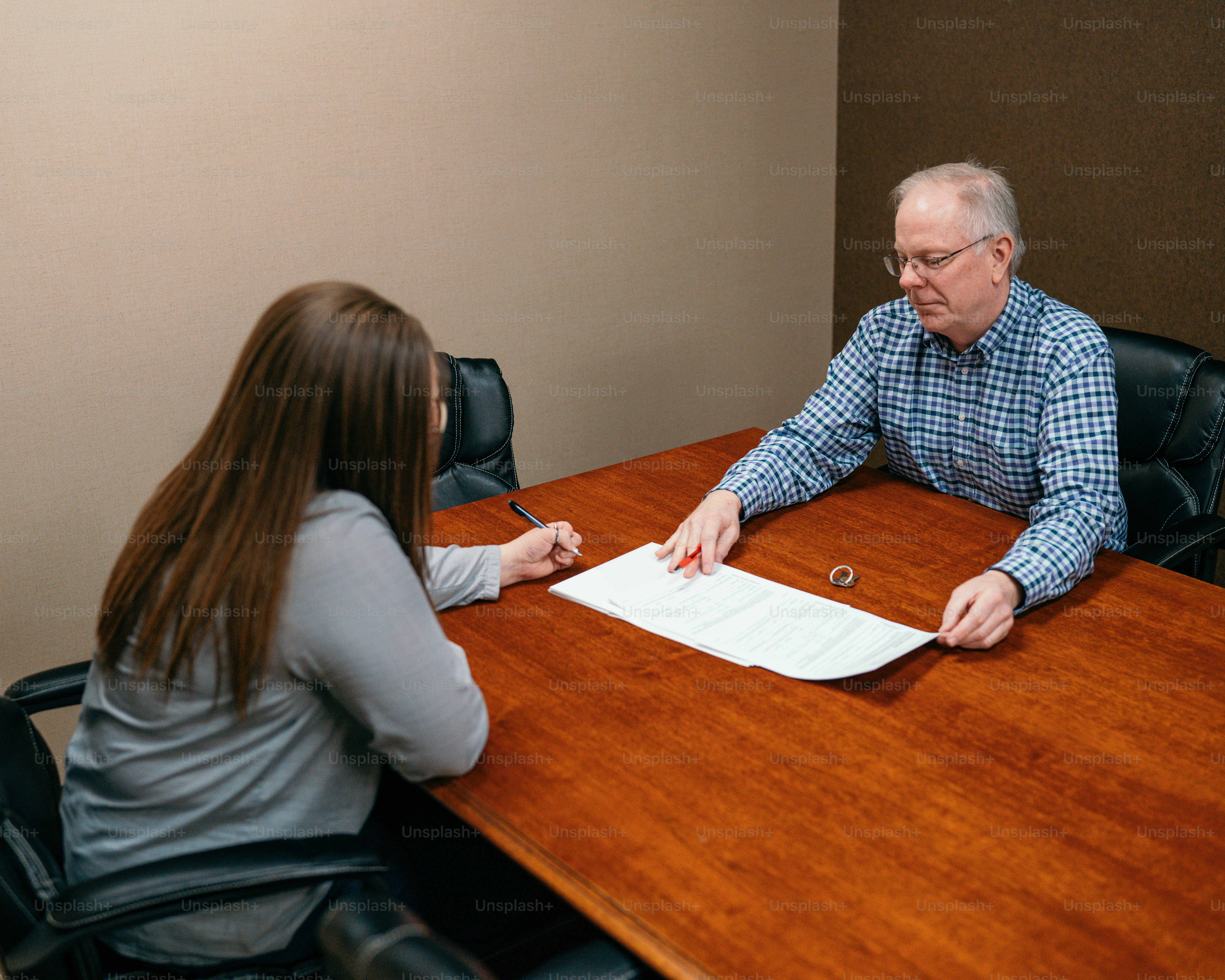 a man and woman sitting at a table signing papers