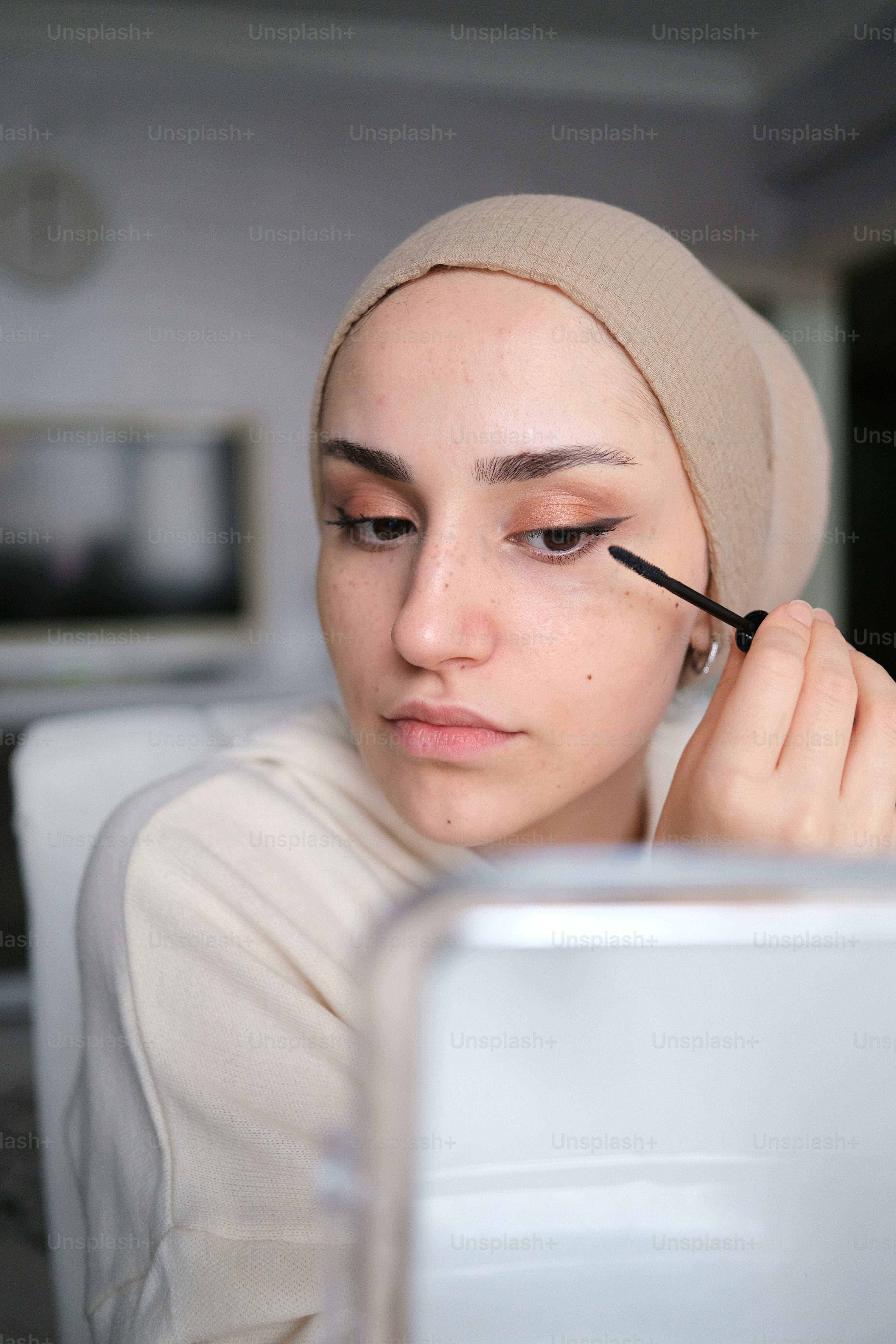 a woman is putting mascara on her eye