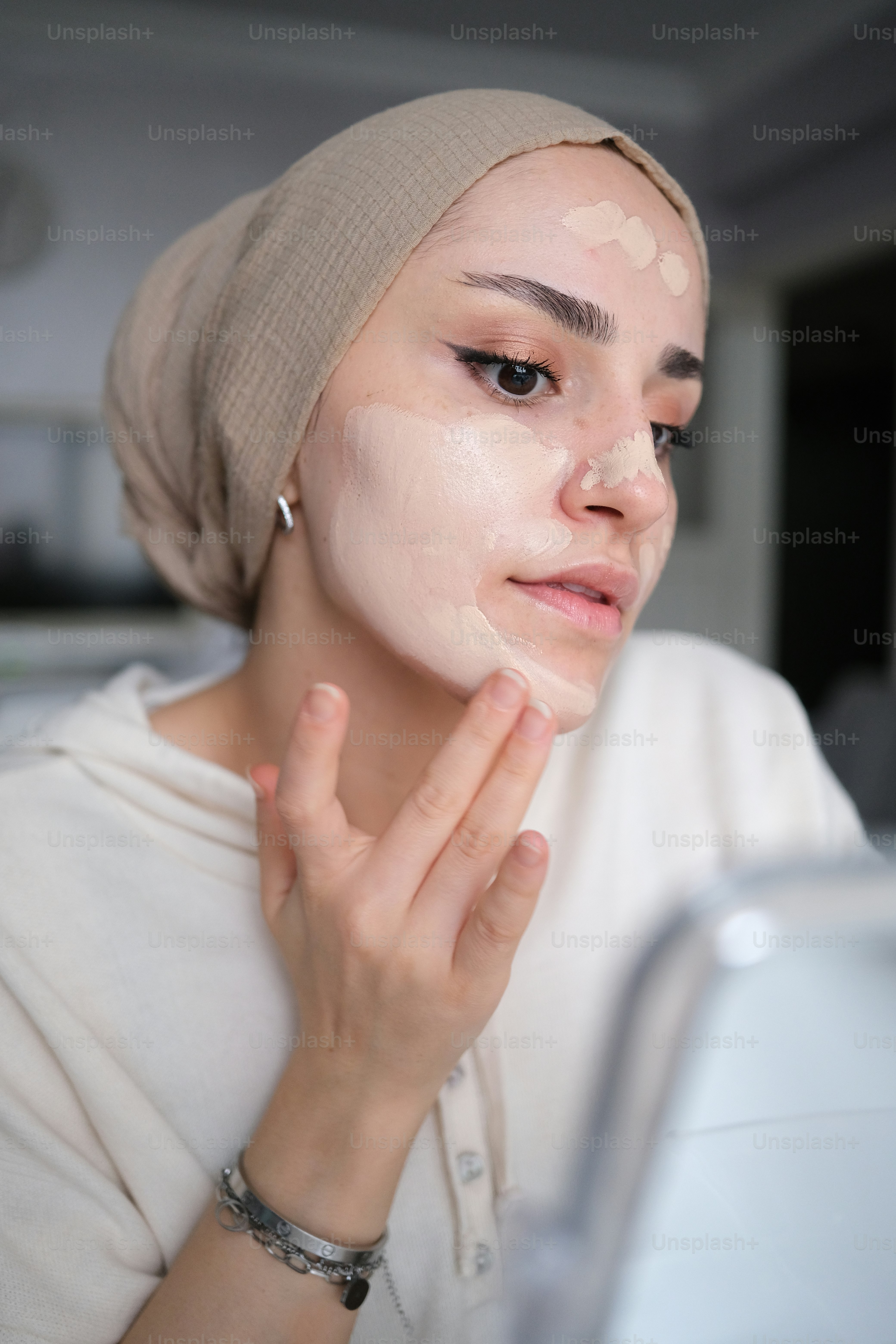a woman with a towel on her head looking at her face